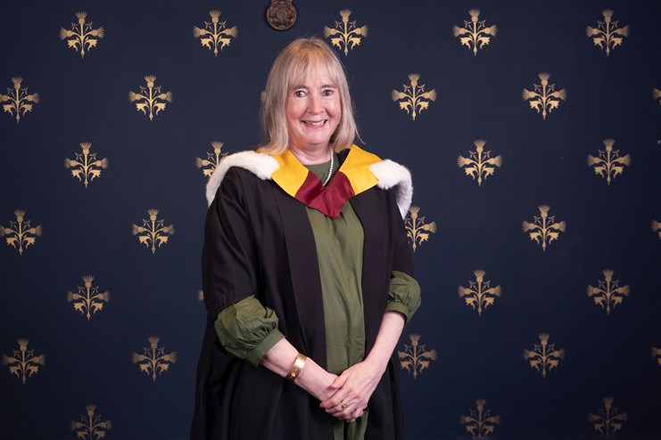 Woman smiling, wearing academic gown and cape