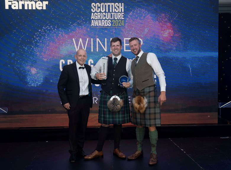 Three men stand in front of a background that says 'Scottish Agriculture Awards 2024'. One of the men is holding a trophy.