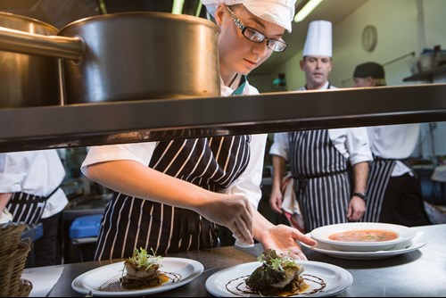 Woman in commerical kitchen preparing food