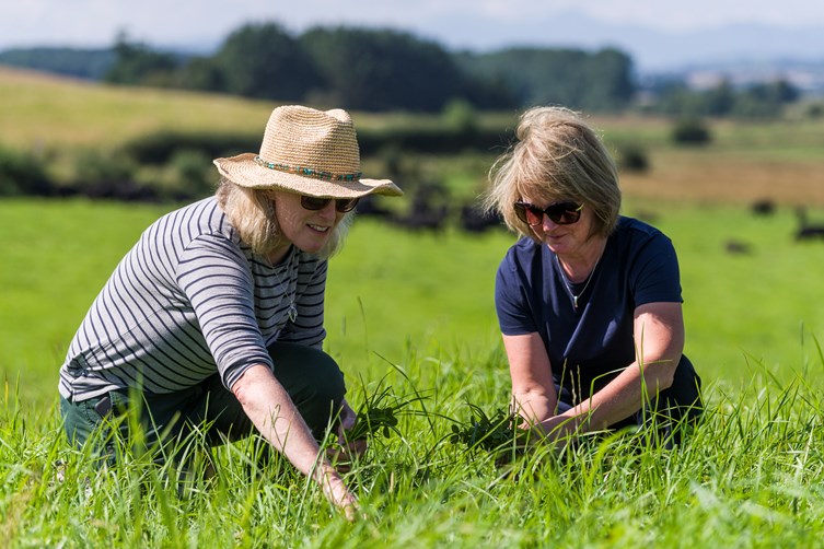 Two women crouching in the grass